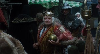 Movie still from “Jabberwocky” (1977), directed by Terry Gilliam – A man dressed as a king holding a golden apple; Medium shot, Low angle