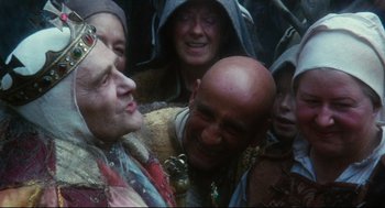 Movie still from “Jabberwocky” (1977), directed by Terry Gilliam – A group of people standing next to each other; Close Up shot, High angle