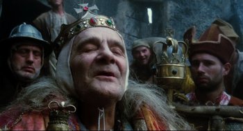 Movie still from “Jabberwocky” (1977), directed by Terry Gilliam – An old man wearing a crown with other people in the background; Close Up shot, Low angle