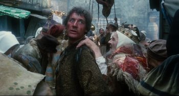Movie still from “Jabberwocky” (1977), directed by Terry Gilliam – A man in medieval garb standing next to other people; Medium shot, Low angle