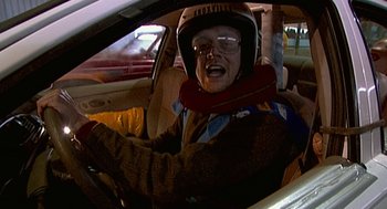 Movie still from “Jackass: The Movie” (2002), directed by Jeff Tremaine – A man in a helmet driving in a car at night; Medium shot, High angle