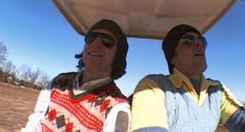 Movie still from “Jackass: The Movie” (2002), directed by Jeff Tremaine – Two men wearing hats and sunglasses are riding a golf cart; Medium shot, Low angle