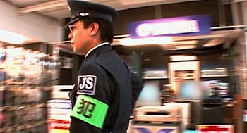 Movie still from “Jackass: The Movie” (2002), directed by Jeff Tremaine – A man in a police uniform is standing in front of a store; Close Up shot, Over the shoulder angle