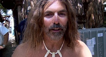 Movie still from “Jackass: The Movie” (2002), directed by Jeff Tremaine – A person with long hair wearing a necklace; Close Up shot, High angle
