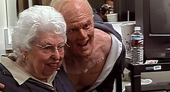 Movie still from “Jackass: The Movie” (2002), directed by Jeff Tremaine – An older man and woman posing for a picture; Close Up shot, High angle