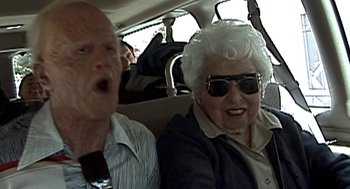 Movie still from “Jackass: The Movie” (2002), directed by Jeff Tremaine – An older man and woman sitting in the back of a car; Medium shot, Low angle