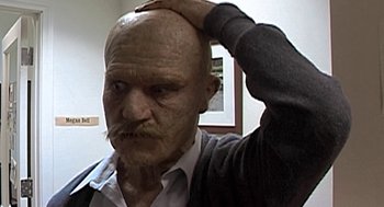 Movie still from “Jackass: The Movie” (2002), directed by Jeff Tremaine – An old man with a bald head touching his head; Close Up shot, High angle