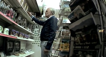 Movie still from “Jackass: The Movie” (2002), directed by Jeff Tremaine – An older man is looking at a shelf in a store; Medium shot, High angle