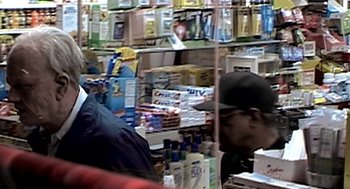 Movie still from “Jackass: The Movie” (2002), directed by Jeff Tremaine – A man in a black hat is at a grocery store; Close Up shot, Over the shoulder angle