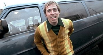 Movie still from “Jackass: The Movie” (2002), directed by Jeff Tremaine – A man in a striped shirt standing next to a van; Medium shot, Low angle
