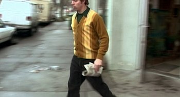 Movie still from “Jackass: The Movie” (2002), directed by Jeff Tremaine – A man walking down the street with a newspaper in his hand; Medium shot, Low angle