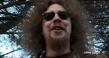 Movie still from “Jackass: The Movie” (2002), directed by Jeff Tremaine – A person wearing sunglasses and a beard; Extreme Close Up shot, Low angle