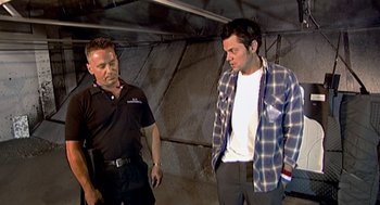 Movie still from “Jackass: The Movie” (2002), directed by Jeff Tremaine – Two men standing next to each other in a room; Medium shot, Low angle