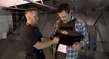 Movie still from “Jackass: The Movie” (2002), directed by Jeff Tremaine – A man in a black shirt and a man in a plaid shirt; Medium shot, Over the shoulder angle