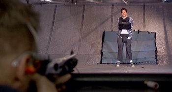 Movie still from “Jackass: The Movie” (2002), directed by Jeff Tremaine – A man standing on a stage holding a microphone; Wide shot, Over the shoulder angle