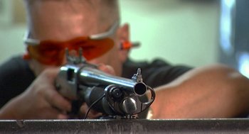Movie still from “Jackass: The Movie” (2002), directed by Jeff Tremaine – A man holding an orange pipe with an orange tube in it; Extreme Close Up shot, Low angle