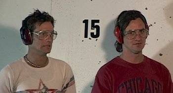Movie still from “Jackass: The Movie” (2002), directed by Jeff Tremaine – Two men wearing headphones and glasses in front of a wall; Close Up shot, Low angle