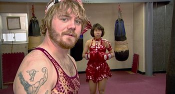 Movie still from “Jackass: The Movie” (2002), directed by Jeff Tremaine – A man and a woman are posing for a picture; Medium shot, High angle