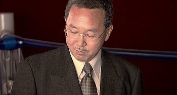 Movie still from “Jackass: The Movie” (2002), directed by Jeff Tremaine – A man in a suit and tie looking down; Close Up shot, High angle