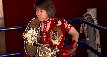Movie still from “Jackass: The Movie” (2002), directed by Jeff Tremaine – A person wearing a red outfit and a pair of boxing gloves; Medium shot, Low angle