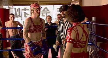 Movie still from “Jackass: The Movie” (2002), directed by Jeff Tremaine – A group of men and women standing next to each other wearing boxing gloves; Medium shot, High angle