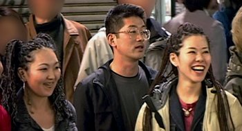 Movie still from “Jackass: The Movie” (2002), directed by Jeff Tremaine – A group of people standing next to each other on the street; Close Up shot, Over the shoulder angle