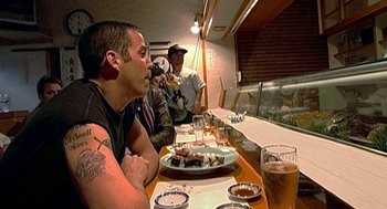 Movie still from “Jackass: The Movie” (2002), directed by Jeff Tremaine – A group of people sitting at a table with food; Medium shot, Over the shoulder angle