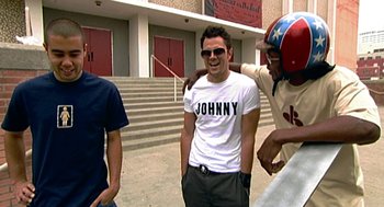 Movie still from “Jackass: The Movie” (2002), directed by Jeff Tremaine – A man in a white t - shirt is smiling for the camera; Medium shot, High angle