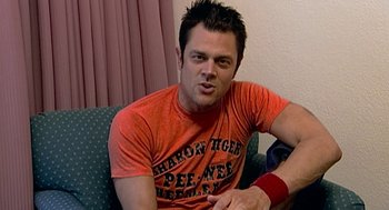 Movie still from “Jackass: The Movie” (2002), directed by Jeff Tremaine – A man sitting on top of a couch in a living room; Close Up shot, High angle