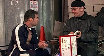 Movie still from “Jackass: The Movie” (2002), directed by Jeff Tremaine – Two men sitting on the ground talking to each other; Medium shot, Over the shoulder angle