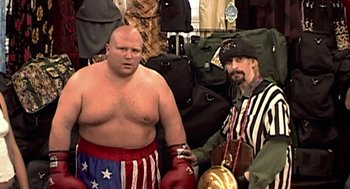 Movie still from “Jackass: The Movie” (2002), directed by Jeff Tremaine – A man in a boxing ring with another man in a hat; Medium shot, Low angle