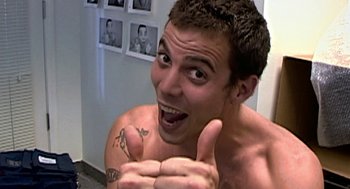 Movie still from “Jackass: The Movie” (2002), directed by Jeff Tremaine – A man with a tattoo on his arm giving a thumbs up; Close Up shot, Low angle