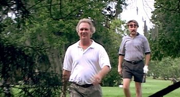 Movie still from “Jackass: The Movie” (2002), directed by Jeff Tremaine – Two men are walking in a park near trees; Medium shot, Low angle