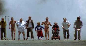 Movie still from “Jackass: The Movie” (2002), directed by Jeff Tremaine – A group of people standing next to each other on a dirt road; Wide shot, Low angle