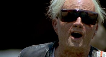 Movie still from “Jackass: The Movie” (2002), directed by Jeff Tremaine – An older man wearing sunglasses and a leather jacket; Close Up shot, Low angle