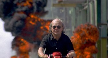 Movie still from “Jackass: The Movie” (2002), directed by Jeff Tremaine – An older man is riding a red bicycle; Wide shot, Low angle