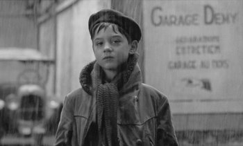 Movie still from “Jacquot of Nantes” (1991), directed by Agnès Varda – A young boy wearing a hat and a coat; Close Up shot, Low angle