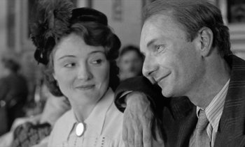 Movie still from “Jacquot of Nantes” (1991), directed by Agnès Varda – An older man and a younger woman are smiling for the camera; Close Up shot, Over the shoulder angle