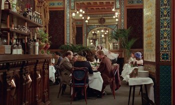 Movie still from “Jacquot of Nantes” (1991), directed by Agnès Varda – A group of people sitting around a table in a restaurant; Extreme Wide shot, High angle
