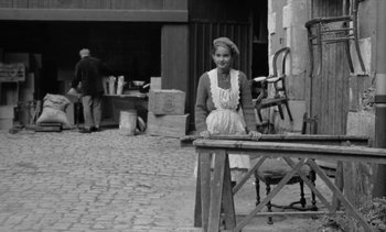 Movie still from “Jacquot of Nantes” (1991), directed by Agnès Varda – A woman standing in front of a table; Wide shot, High angle