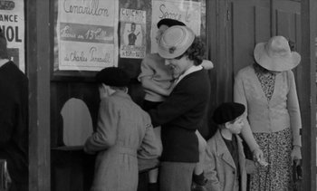 Movie still from “Jacquot of Nantes” (1991), directed by Agnès Varda – An old black and white photo of a woman holding a baby; Medium shot, High angle
