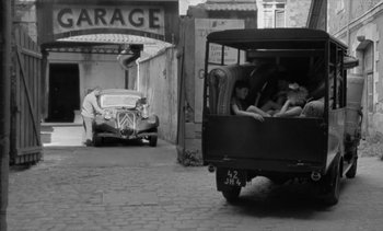 Movie still from “Jacquot of Nantes” (1991), directed by Agnès Varda – An old car parked on the side of the street; Wide shot, High angle