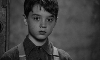 Movie still from “Jacquot of Nantes” (1991), directed by Agnès Varda – A young boy is looking into the camera; Close Up shot, High angle