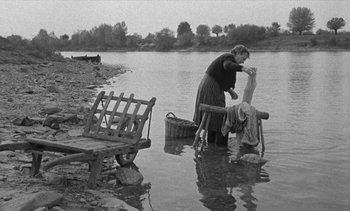 Movie still from “Jacquot of Nantes” (1991), directed by Agnès Varda – An older woman washing a man in the water; Wide shot, High angle