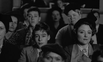 Movie still from “Jacquot of Nantes” (1991), directed by Agnès Varda – Black and white photograph of people sitting in a theater; Medium shot, High angle