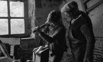 Movie still from “Jacquot of Nantes” (1991), directed by Agnès Varda – Two people standing next to each other near a window; Medium shot, High angle