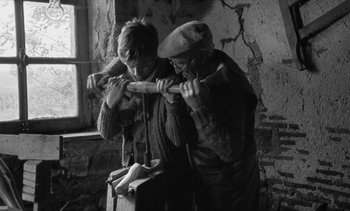 Movie still from “Jacquot of Nantes” (1991), directed by Agnès Varda – Two people are working on a project in a room; Medium shot, High angle