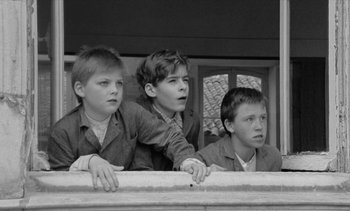 Movie still from “Jacquot of Nantes” (1991), directed by Agnès Varda – Three young boys are looking over a railing; Medium shot, Low angle