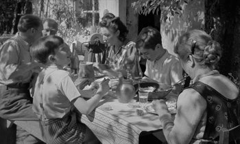 Movie still from “Jacquot of Nantes” (1991), directed by Agnès Varda – A group of people sitting around a table; Medium shot, High angle