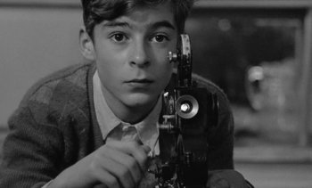 Movie still from “Jacquot of Nantes” (1991), directed by Agnès Varda – A young man holding an old fashioned movie camera; Close Up shot, High angle